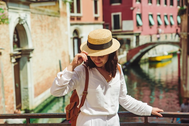 Young pretty woman traveler standing at venice bridge cross canal