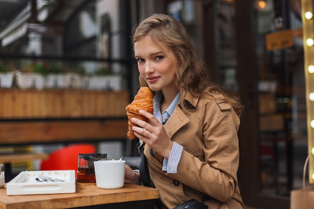 思慮深くトレンチコートを着た若いきれいな女性