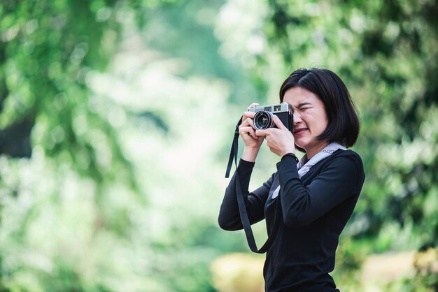 Young pretty woman use camera taking photo in nature park