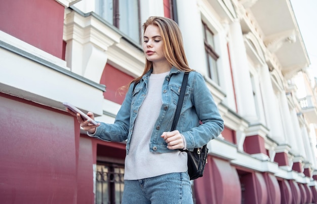 Young pretty woman using smartphone and holding a cup of coffee in the city