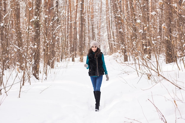 화창한 날에 겨울 눈 덮인 공원에서 산책하는 젊은 예쁜 여자