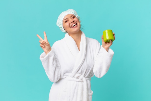 Young pretty woman wearing bathrobe and holding a clean product bottle