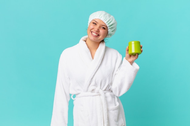 Young pretty woman wearing bathrobe and holding a clean product bottle