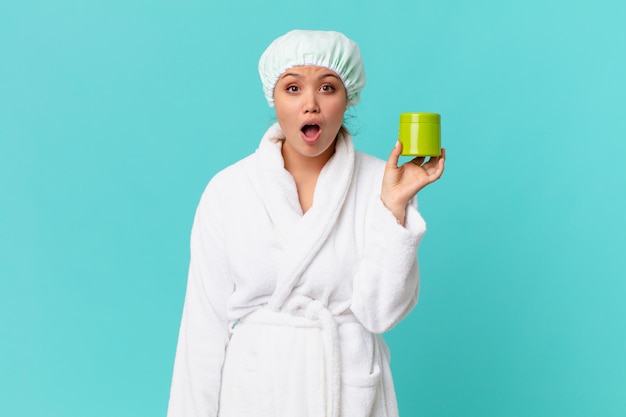 young pretty woman wearing bathrobe and holding a clean product bottle