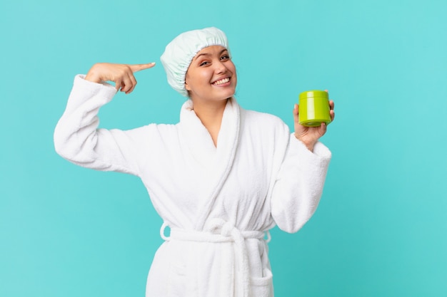 Young pretty woman wearing bathrobe and holding a clean product bottle