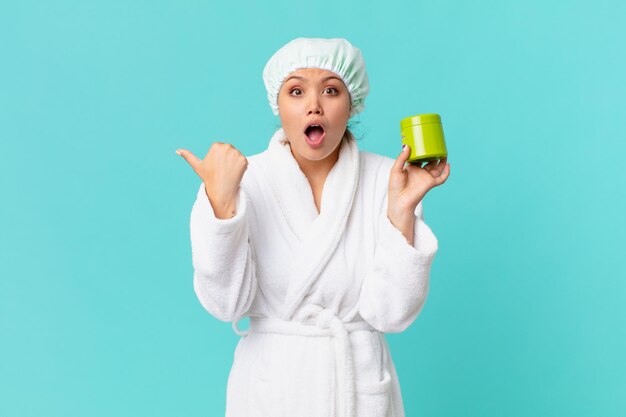 Young pretty woman wearing bathrobe and holding a clean product bottle