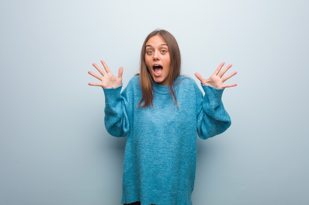 Young pretty woman wearing a blue sweater celebrating a victory or success