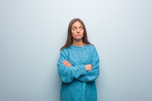 Young pretty woman wearing a blue sweater tired and bored