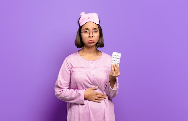 Young pretty woman wearing pajamas and holding pills