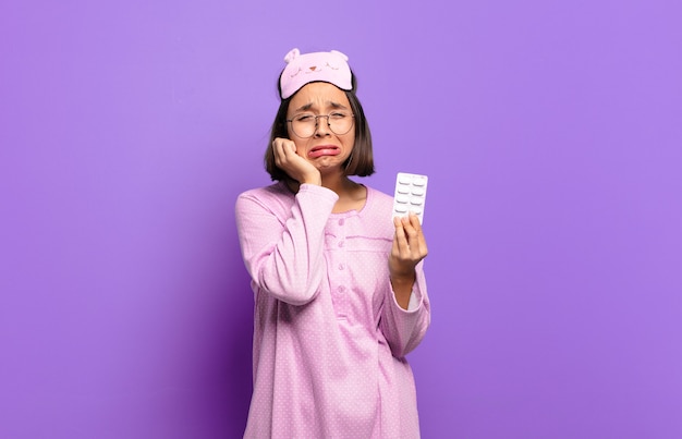 Young pretty woman wearing pajamas and holding pills