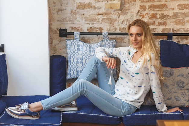 Young pretty woman wearing in white blouse resting on sofa in cafe