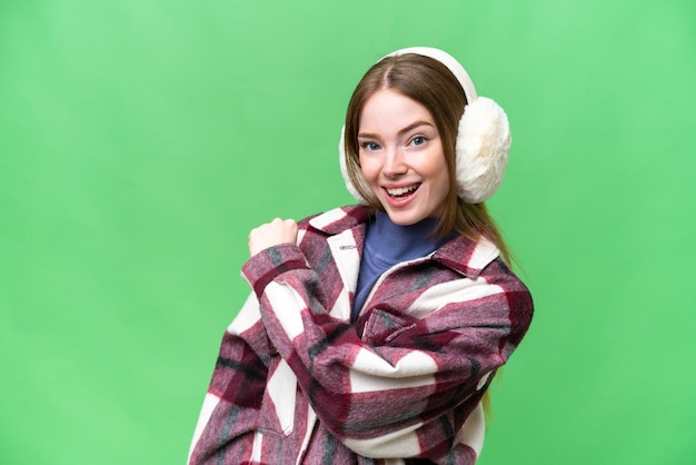 Young pretty woman wearing winter muffs over isolated chroma key background celebrating a victory