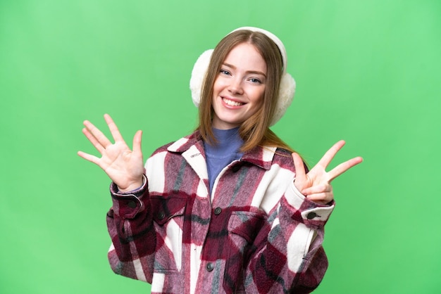 Молодая красивая женщина в зимних муфтах на изолированном фоне хроматического ключа, считая восемь пальцами