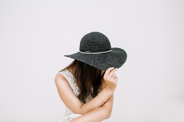 Young pretty woman in white dress with black hat