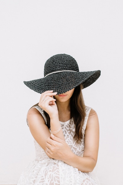 Young pretty woman in white dress with black hat