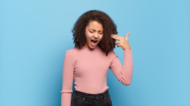 Photo young pretty woman with afro hair and pink sweater posing on blue wall