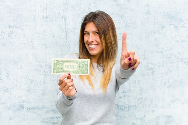 Young pretty woman with banknotes against grunge wall