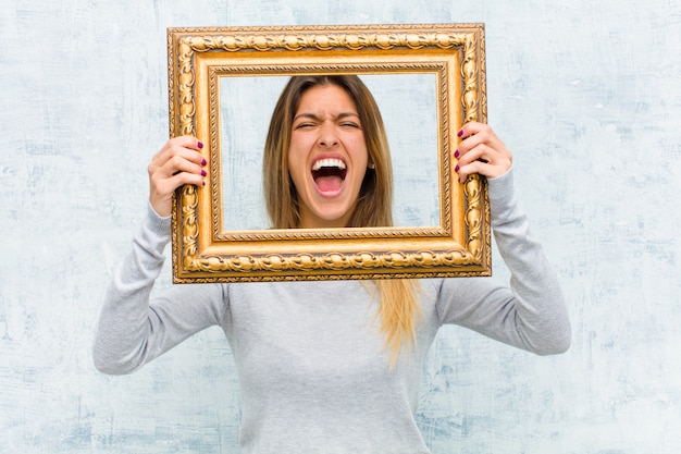 Young pretty woman with a baroque frame against grunge wall