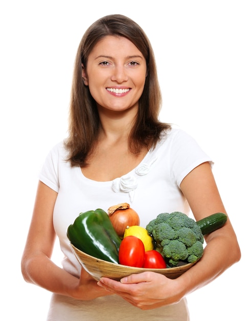 a young pretty woman with a basket full of vegetables over white background