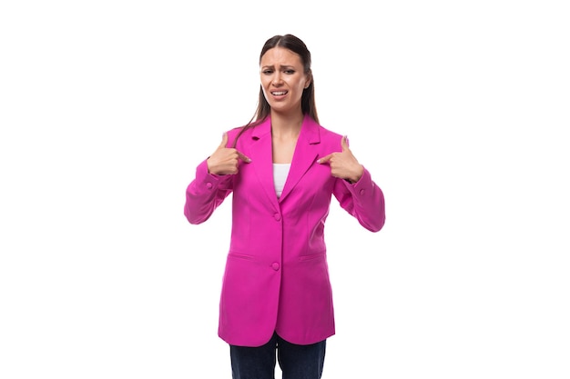 黒髪のストレートの若いきれいな女性は、アトリエで縫い付けられたデザイナーのピンクのジャケットを着ています
