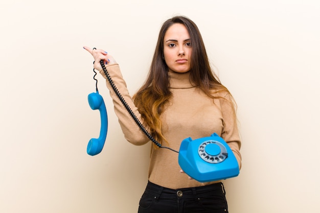 Foto giovane donna graziosa con un telefono vintage blu