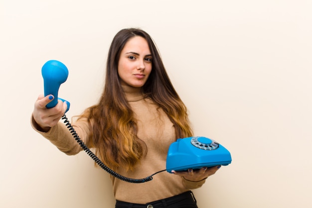 Young pretty woman with a blue vintage phone