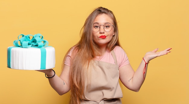 Young pretty woman with confused expression and birthday cake