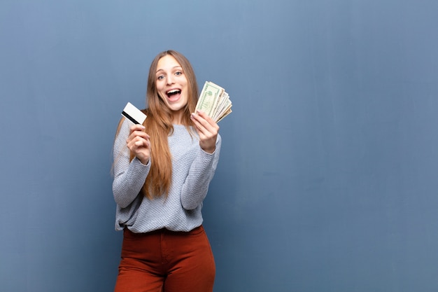 Young pretty woman with dollar banknotes against blue  with a copyspace