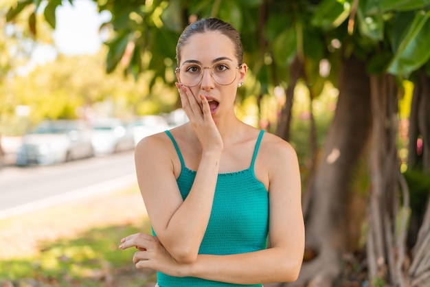 Young pretty woman with glasses at outdoors surprised and shocked while looking right