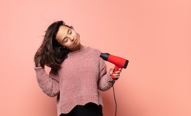 ヘアドライヤーを持つ若いきれいな女性