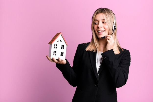 Young pretty woman with headset and a house model real state\
concept