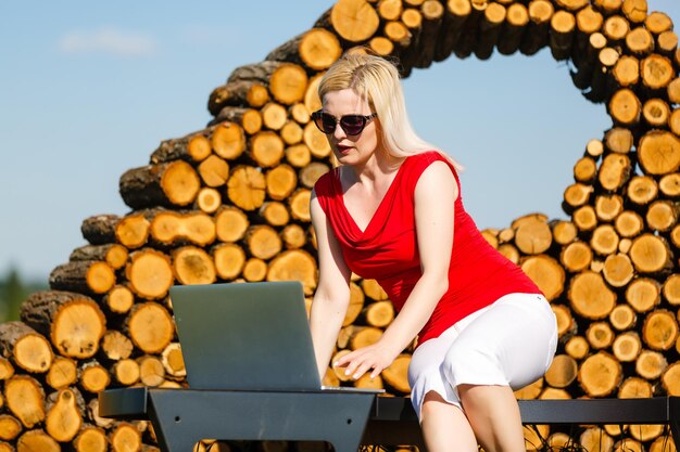 Young pretty woman with laptop on the bench in a park