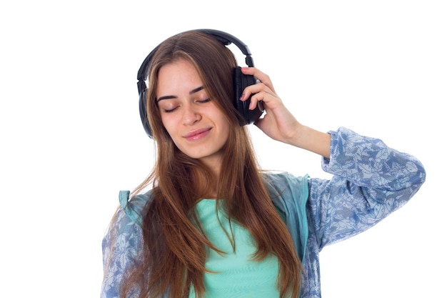 Giovane donna graziosa con i capelli lunghi in camicia che ascolta la musica in cuffia con gli occhi chiusi