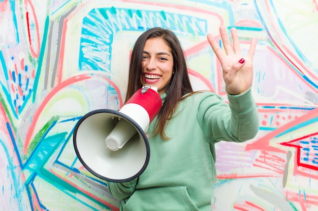 Young pretty woman with a megaphone against graffiti wall