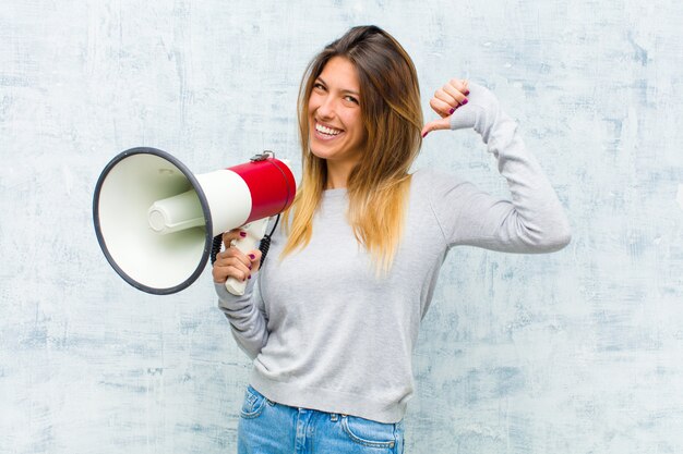 グランジの壁にメガホンを持つ若いきれいな女性