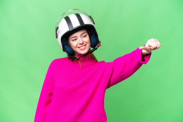 Молодая красивая женщина в мотоциклетном шлеме на изолированном фоне хроматического ключа показывает жест "большой палец вверх"