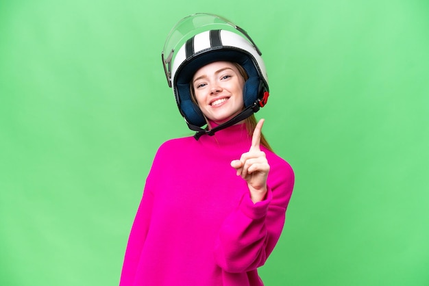 Photo young pretty woman with a motorcycle helmet over isolated chroma key background showing and lifting a finger