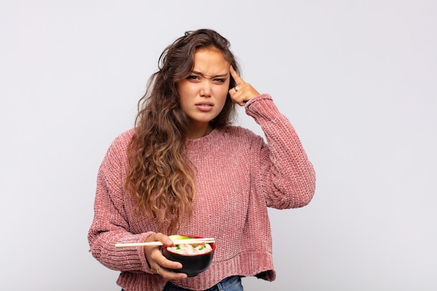 Foto giovane bella donna con le tagliatelle che si sente confusa e perplessa, mostrando che sei pazzo, pazzo o fuori di testa