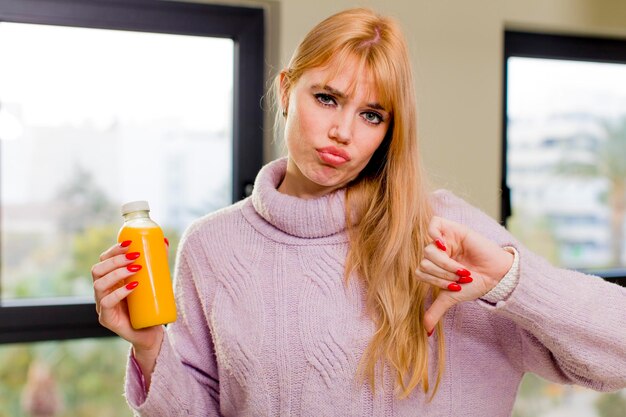 Young pretty woman with an orange juice at home interior