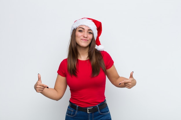 サンタの帽子を持つ若いきれいな女性。クリスマスのコンセプト。