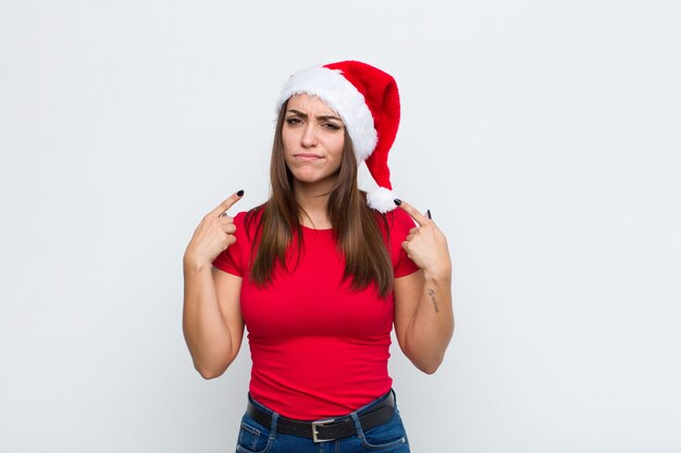 サンタの帽子を持つ若いきれいな女性。クリスマスのコンセプト。