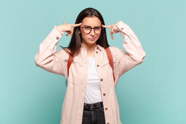 Young pretty woman with a serious and concentrated look, brainstorming and thinking about a challenging problem. student concept