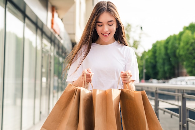 young pretty woman with shopping bags walking on the city street