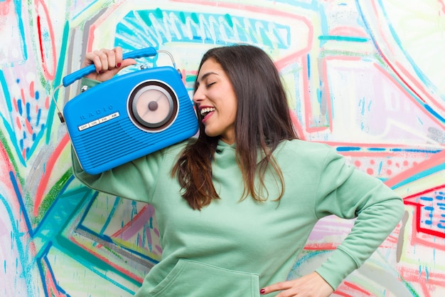 Foto giovane donna graziosa con una radio vintage contro il muro di graffiti