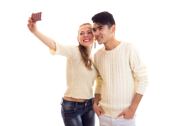 Young pretty woman with young pleasant man with dark hair in white sweaters holding white cups