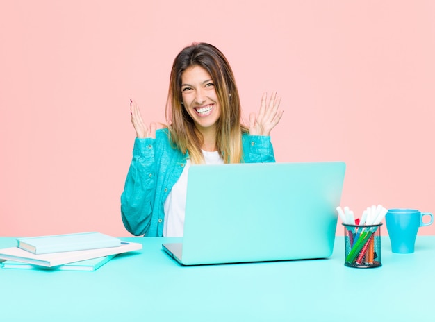 Young pretty woman working with a laptop looking shocked and astonished, with jaw dropped in surprise when realizing something unbelievable