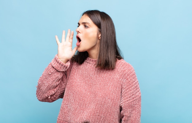 Photo young pretty woman yelling loudly and angrily to copy space on the side