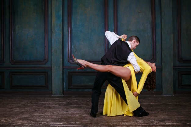 Foto giovane donna graziosa in abito giallo e uomo che balla il tango