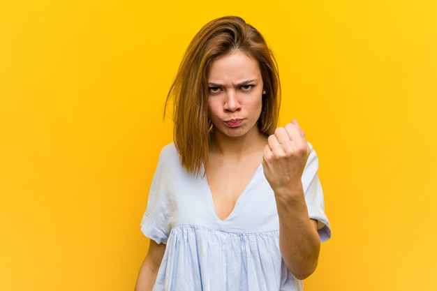 Giovane donna abbastanza giovane che mostra il pugno con con espressione facciale aggressiva.