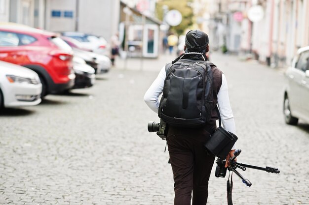 Young professional african american videographer holding professional camera with tripod pro equipment Afro cameraman wearing black duraq making a videos